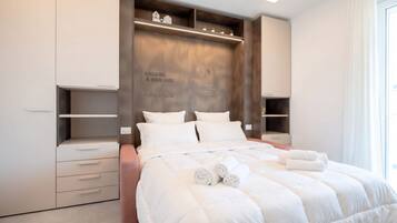 Una camera da letto moderna con un letto grande, spazio contenitivo integrato e una frase motivazionale sulla testiera.