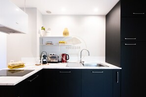 A modern kitchen with a built-in stove, a sink, and a coffee maker. - Appt Ermitage - Hossegor center - Terrace - Park (Soorts-Hossegor)