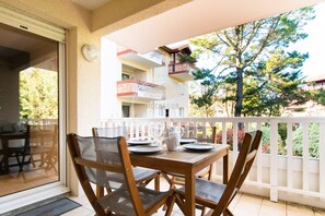 Ein Balkon mit Esstisch, Stühlen und Blick auf ein Wohnhaus.