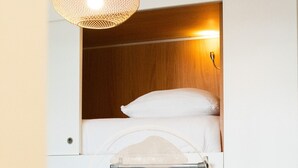 Ein kleines Zimmer mit einem Etagenbett, einer Pendelleuchte und einer Schlafcouch.