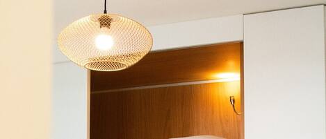 Une petite pièce comprenant un lit superposé, un luminaire suspendu et un canapé.