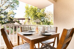 A wooden table set with plates, cutlery, and a pitcher on a balcony with a white railing. - Appt Ermitage - Hossegor center - Terrace - Park (Soorts-Hossegor)