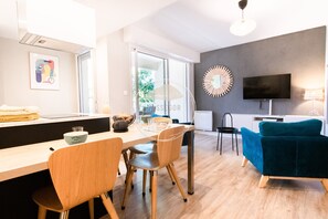 A modern living space with a dining area, a TV, and a sofa.