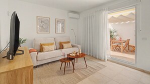 Uma sala de estar moderna com sofá, mesa de centro, TV e obras de arte.