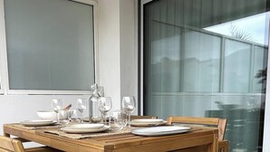 A dining table set with plates, glasses, and a pitcher, positioned in a room with large windows and a view of the outside. - Appt Brémontier 3 - Hossegor center - Terrace (Soorts-Hossegor)