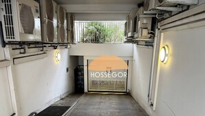 A hallway with air conditioning units on the walls, a metal gate, and a sign reading 'HOSSEGOR PROPERTY'. - Appt Brémontier 3 - Hossegor center - Terrace (Soorts-Hossegor)