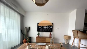 A dining area with a wooden table set for four, a cactus decoration, and a wall sign for 'HOSSEGOR PROPERTIES'. - Appt Brémontier 3 - Hossegor center - Terrace (Soorts-Hossegor)