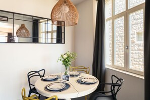 Un comedor con una mesa redonda para cuatro personas, un florero con flores y una lámpara colgante.