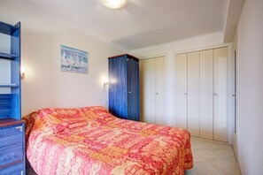 Ein Schlafzimmer mit einem Bett, einem Kleiderschrank, einem Bild und einer Tür.
