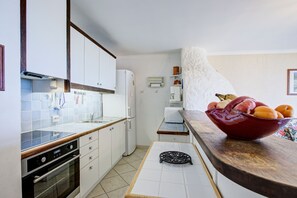 Eine kleine Küche mit weißen Schränken, einem Einbauofen und einer Holz Arbeitsplatte.