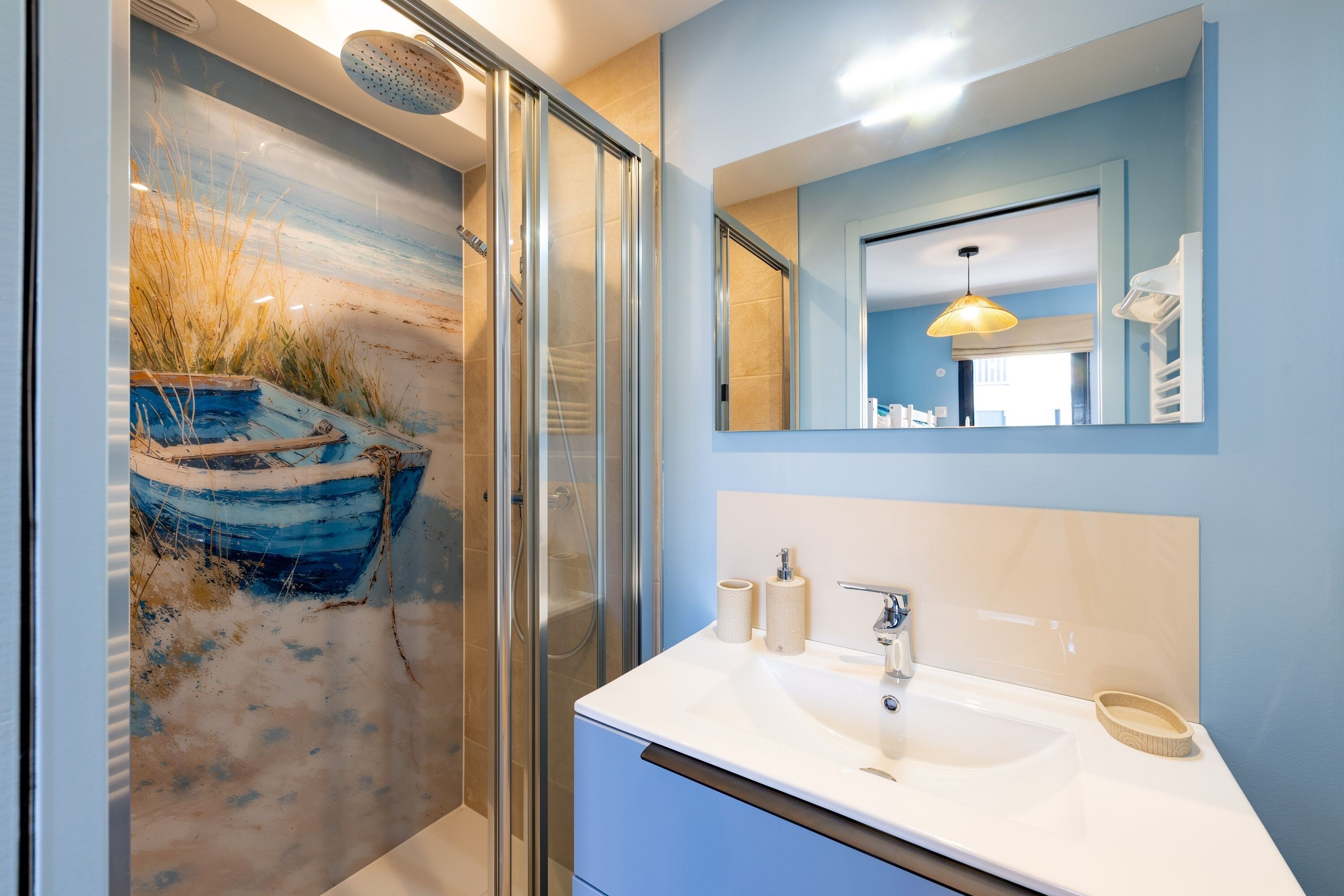 Une salle de bain moderne avec une douche à parois de verre, un grand miroir et un lavabo doté d’un porte-serviettes.