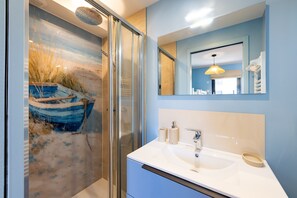 A modern bathroom with a glass-enclosed shower, a large mirror, and a sink with a towel rack. - Ker Mor - À 150 m de la plage (Quiberon)