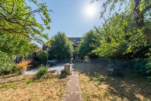 A pathway leading through a garden with various plants and trees, a bench, and a building in the background. - La Maison Rabier - Gare La Barre Ormesson à 300 m (Deuil-la-Barre)
