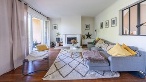 Ein Wohnzimmer mit einer Couch, Sesseln, einem Couchtisch und einem Kamin.