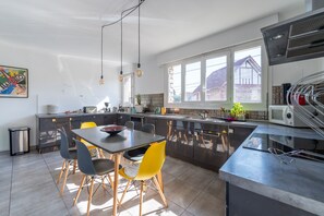 A modern kitchen with a dining area, large windows, and a view of the neighborhood. - La Maison Rabier - Gare La Barre Ormesson à 300 m (Deuil-la-Barre)