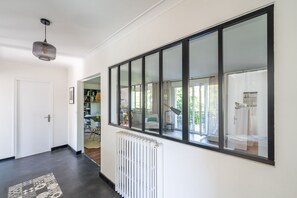 Ein Flur mit Heizkörper, einem großen Fenster und einer Tür zu einem Zimmer.