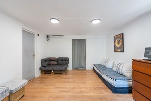 Ein gemütlicher Raum mit Schlafsofa, Bett, Holzkommode und einem Bild an der Wand.