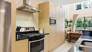 A modern kitchen with stainless steel appliances, wooden cabinetry, and a built-in microwave. - Stylish 4 Ensuite Home Near Disney, Free BBQ Grill (Kissimmee)