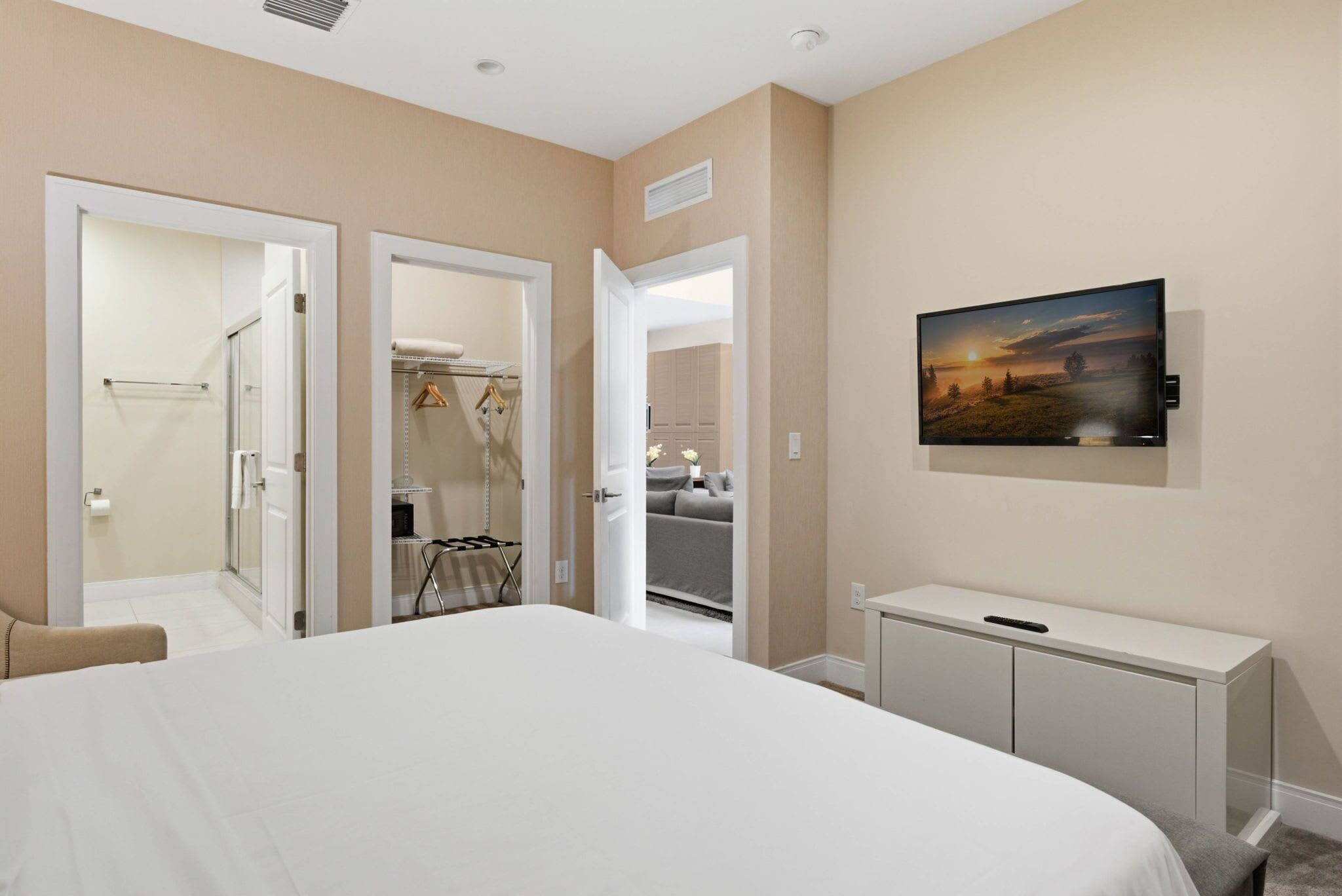 A hotel room with a large bed, a bedside table, a wardrobe, and a painting on the wall.