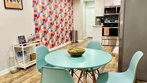 Una cucina moderna con zona pranzo, sedie color petrolio e un tavolo rotondo.