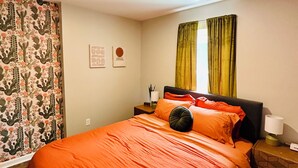 Una camera con un letto, un comodino, una lampada e una finestra con tende.