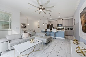 A modern living room with a sofa, coffee table, and a ceiling fan. - Family Friendly Home, Private Pool, Near Disney (Kissimmee)
