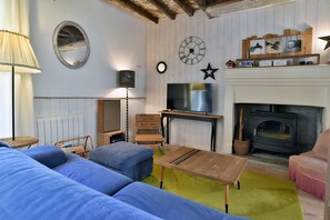 Ein gemütliches Wohnzimmer mit Kamin, Fernseher und einem großen Spiegel an der Wand.