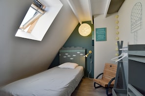 A small, modern bedroom with a sloped ceiling, a single bed, a wooden chair, a desk, and a wall-mounted light fixture. - Retour aux Sources - Jolie maison familiale pour 6 (Ploubalay)