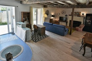 A cozy living room with a blue sofa, a wooden table, and a fireplace. - Retour aux Sources - Jolie maison familiale pour 6 (Ploubalay)