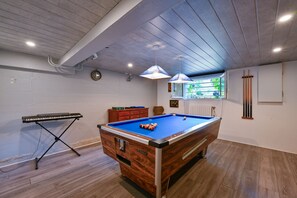 Ein Billardtisch mit blauer Spielvliesbahn, ein Billardständer und eine Tastatur in einem Raum mit Holzboden und weißen Wänden.