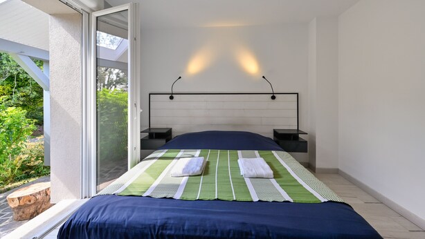 A bedroom with a bed, two bedside tables, a window with a view of greenery, and a skylight. - Pessun - Maison pour 8 avec jardin (Berric)