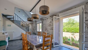 A modern kitchen with a large island, a staircase, and a view of the garden. - Pessun - Maison pour 8 avec jardin (Berric)