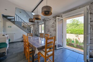 A modern kitchen with a large island, a staircase, and a view of the garden. - Pessun - Maison pour 8 avec jardin (Berric)