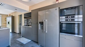A modern kitchen with stainless steel appliances, a built-in oven, and a microwave. - Pessun - Maison pour 8 avec jardin (Berric)