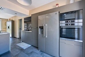 A modern kitchen with stainless steel appliances, a built-in oven, and a microwave. - Pessun - Maison pour 8 avec jardin (Berric)