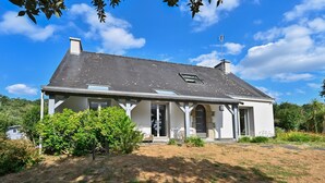 A single-story house with a sloped roof, a chimney, and a small attached garage. - Pessun - Maison pour 8 avec jardin (Berric)