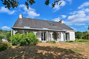 A single-story house with a sloped roof, a chimney, and a small attached garage. - Pessun - Maison pour 8 avec jardin (Berric)