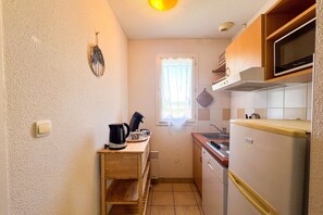 A compact kitchen with a stove, sink, and a microwave. - L’Évasion Claire Rive - Proche domaines viticoles (Prayssac)