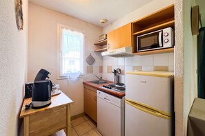 A compact kitchen with a built-in microwave, a stove, and a dishwasher. - L’Évasion Claire Rive - Proche domaines viticoles (Prayssac)