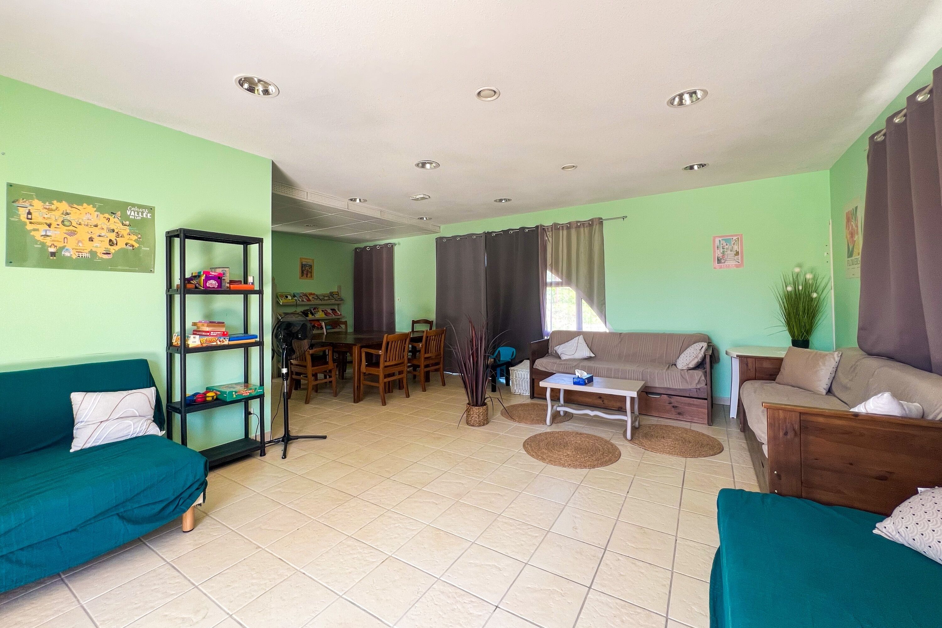 Ein Wohnzimmer mit türkisfarbenen Sofas, einem Esstisch und einer Küchenzeile.