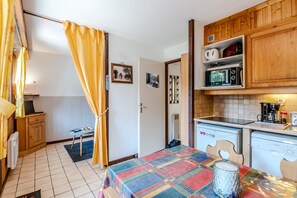 Eine kleine Küche mit Mikrowelle, Kaffeemaschine und Geschirrspüler von Bosch. In der Mitte steht ein Tisch mit einer bunten Tischdecke.