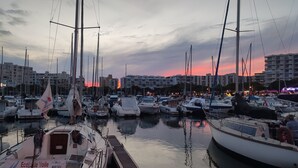 A marina with multiple boats docked, a wooden dock, and buildings in the background. - Le Flamant Rose - Climatisé et à 200 m de la plage (Mauguio)