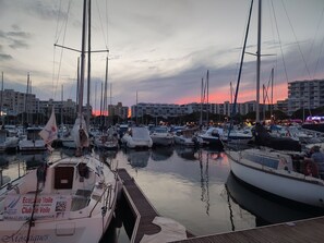 A marina with multiple boats docked, a wooden dock, and buildings in the background. - Le Flamant Rose - Climatisé et à 200 m de la plage (Mauguio)