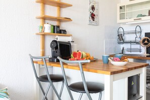 A compact kitchen with a wooden countertop, a coffee machine, a fruit bowl, and a microwave. - Le Flamant Rose - À 200 m de la plage (Mauguio)