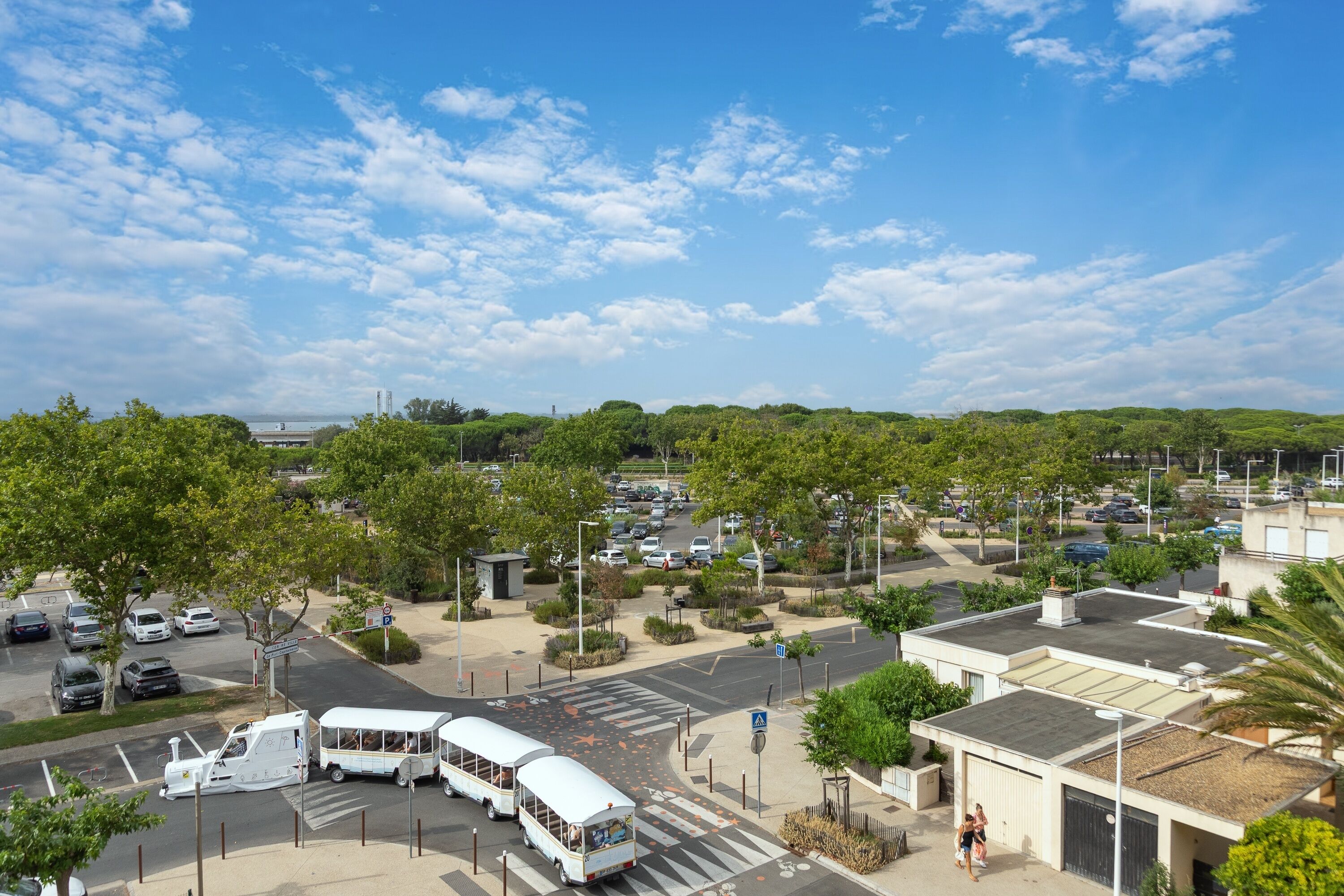 A parking lot with multiple vehicles, including buses, and a pedestrian crossing.