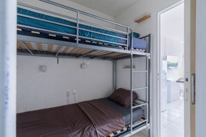 A bunk bed room with a door to the right. - Le Flamant Rose - À 200 m de la plage (Mauguio)