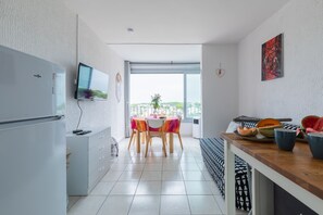A modern kitchen with a built-in fridge, a flat-screen TV, and a dining area with a table and chairs. - Le Flamant Rose - Climatisé et à 200 m de la plage (Mauguio)