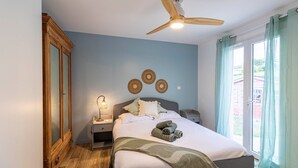A bedroom with a bed, nightstands, a ceiling fan, and a window with curtains. - L’Horizon de Ribérac - Piscine privée chauffée (Saint-Martin-de-Ribérac)