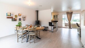 A modern living space with a dining area, kitchen, and a large window. - L’Horizon de Ribérac - Piscine privée chauffée (Saint-Martin-de-Ribérac)