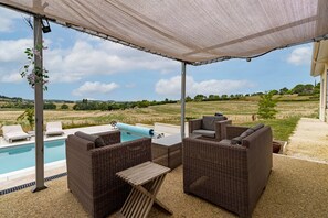 Ein Außenbereich mit Korbmöbeln, einem Pool und Blick auf die Landschaft.